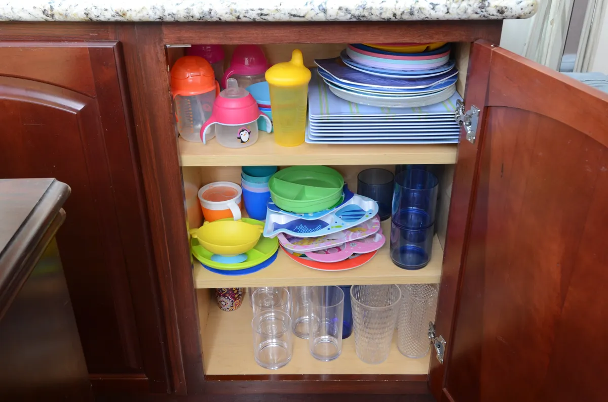 Colorful cups, plates, and bowls are neatly organized in storage spaces, suggesting a playful and family-friendly dining experience. The vibrant atmosphere hints at special touches like a kids' table and festive occasions.