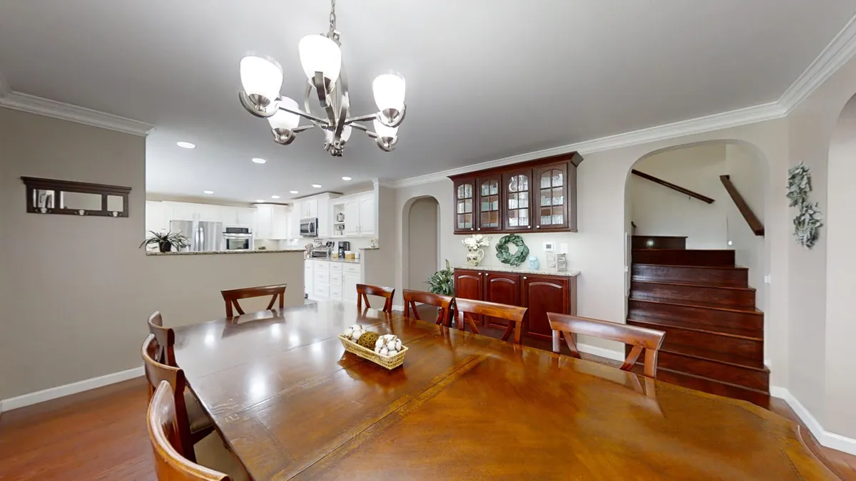 A warm, inviting dining area is featured here, with a large table set beneath a chandelier, adjacent to the kitchen and surrounded by elegant cabinetry. The space is ideal for family dinners, holiday parties, and milestone celebrations.