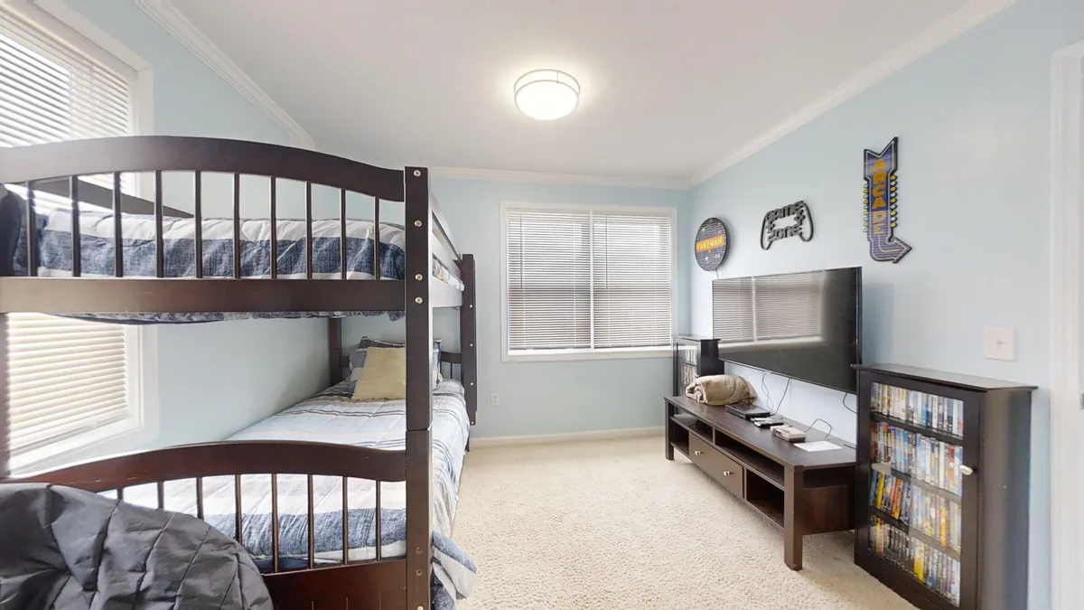 A cozy nook designed for kids, featuring a bunk bed, television, shelves brimming with DVDs, and fun wall decor. The space invites movie nights, gaming sessions, and quiet downtime, making it an ideal zone for young guests to relax and play.