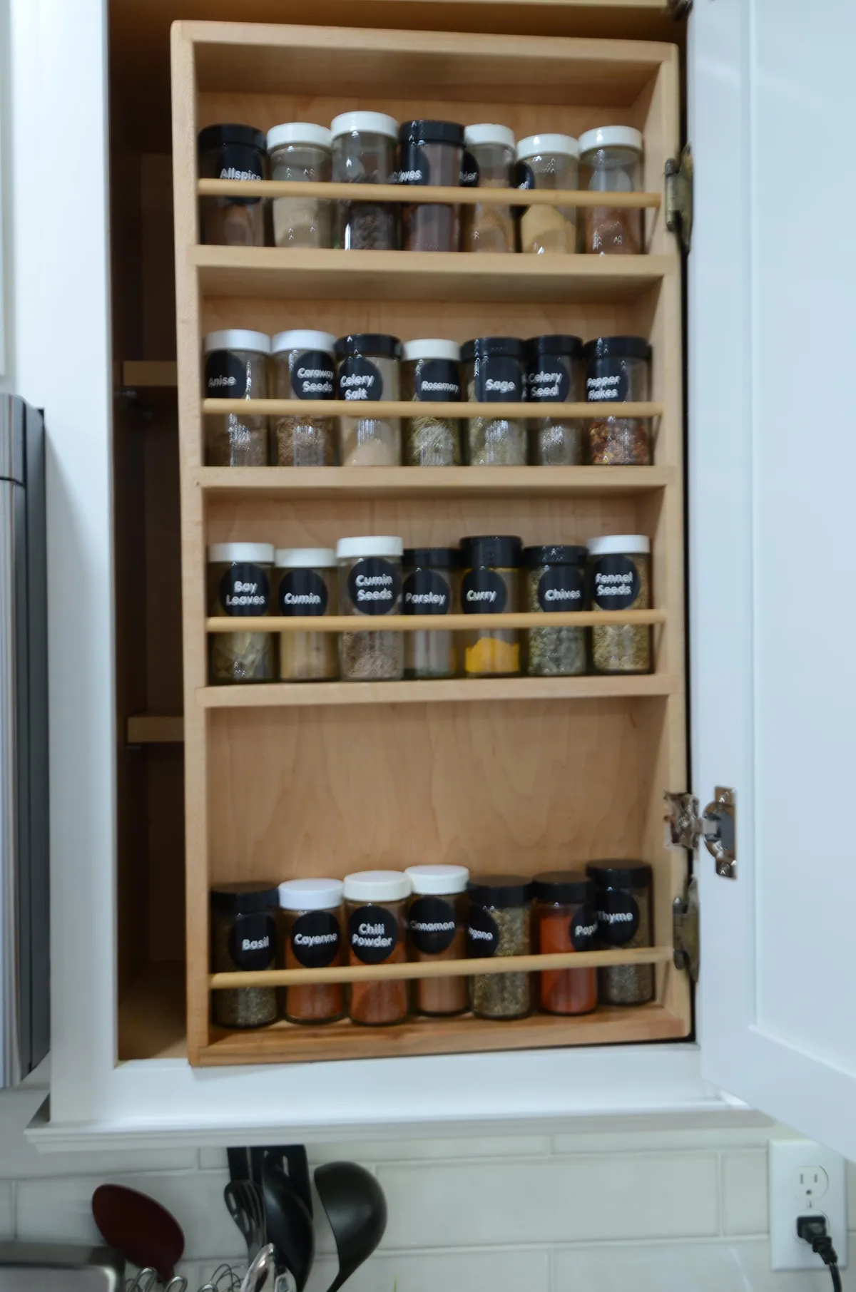 A close-up view of neatly arranged spice jars on wooden shelves, creating a functional and inviting atmosphere. The display emphasizes attention to culinary detail and readiness for a variety of cooking adventures.
