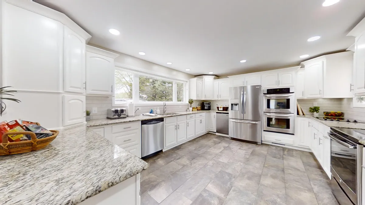 This interior kitchen shot highlights a spacious, modern kitchen with a granite countertop, stainless steel appliances, and large windows. The layout is ideal for group cooking, entertaining, and creating memorable family meals.
