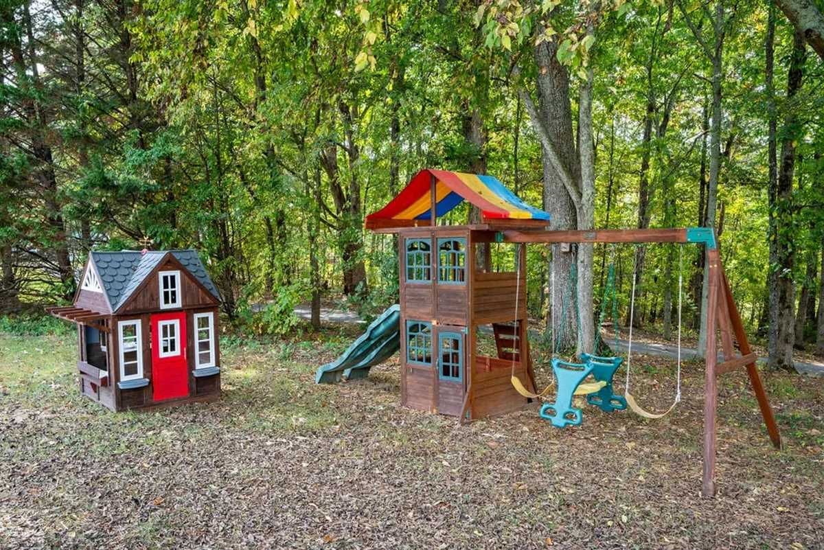 A vibrant exterior view featuring a spacious play structure with slides and swings, alongside a whimsical playhouse. Children are seen playing and laughing, while adults enjoy family time nearby, evoking scenes of joyful family gatherings and imaginative outdoor play.