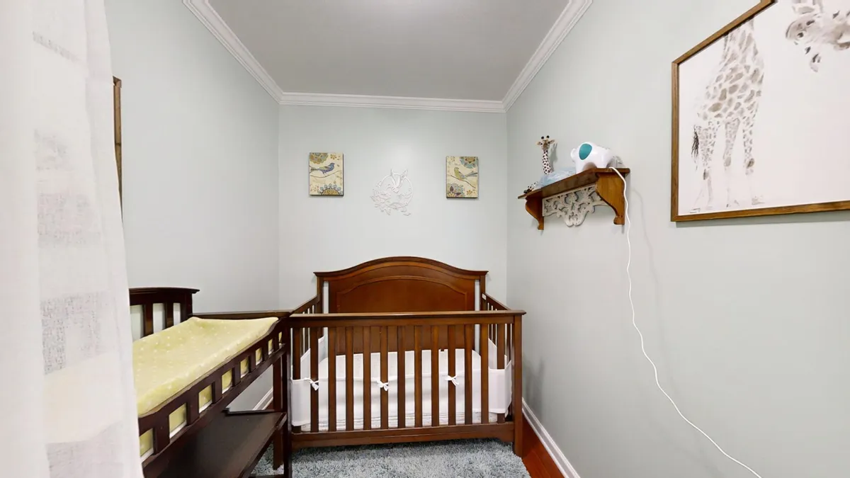 A tranquil nursery space featuring a crib, whimsical giraffe artwork, and carefully curated shelf decor. The scene is gentle and inviting, ideal for napping, reading bedtime stories, and safe play for infants and toddlers.